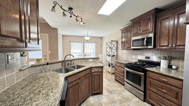 kitchen with stainless steel appliances, visible vents, backsplash, a sink, and light stone countertops