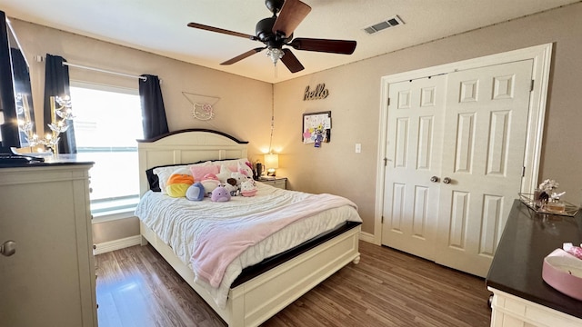 bedroom featuring a ceiling fan, wood finished floors, visible vents, and baseboards