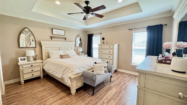 bedroom featuring light wood-style flooring, baseboards, a raised ceiling, and ornamental molding