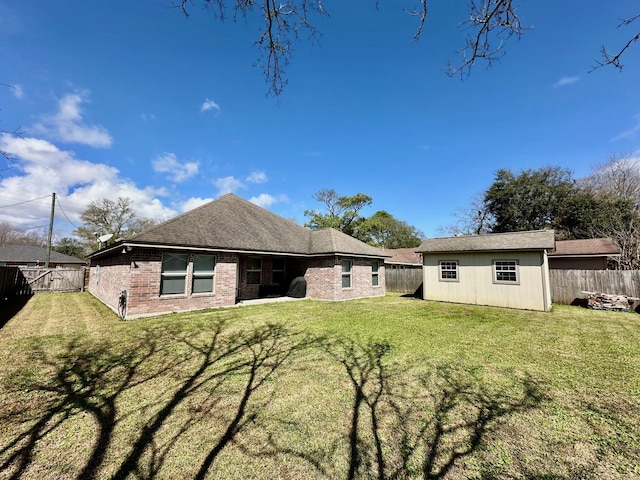 rear view of house featuring an outbuilding, a fenced backyard, and a lawn