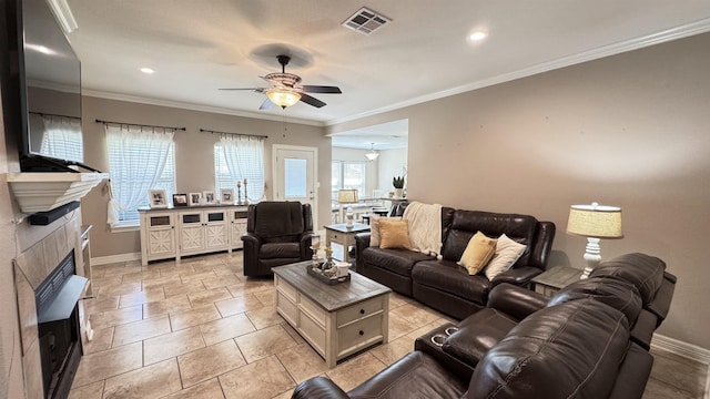 living room with a wealth of natural light, a tile fireplace, visible vents, and crown molding