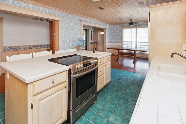 kitchen with wallpapered walls, tile counters, wood ceiling, stainless steel electric stove, and a sink