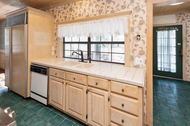 kitchen featuring a sink, wallpapered walls, dishwasher, and light brown cabinetry