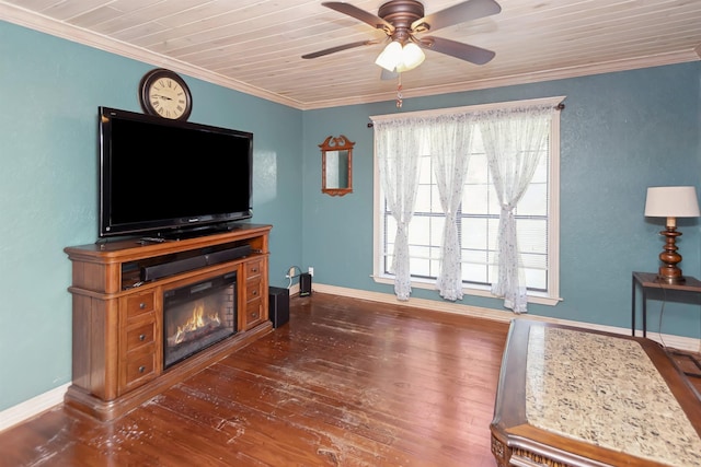 living area featuring baseboards, a ceiling fan, a glass covered fireplace, dark wood-style floors, and ornamental molding