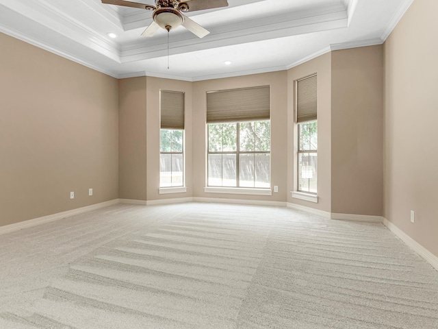 spare room with ceiling fan, a raised ceiling, ornamental molding, and light carpet