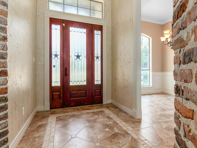 entrance foyer with crown molding and a chandelier