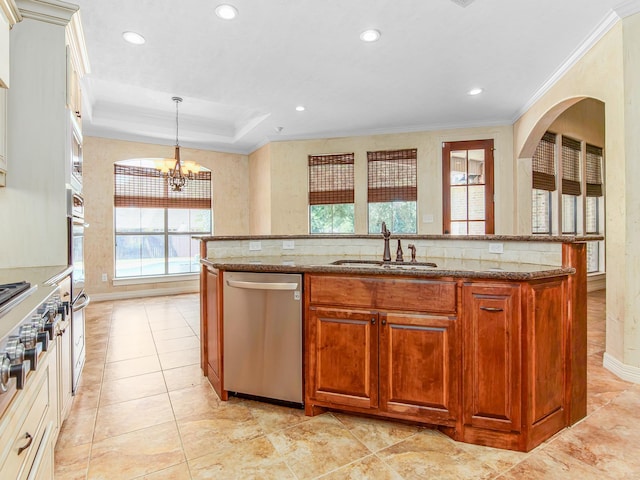 kitchen featuring a center island with sink, hanging light fixtures, sink, appliances with stainless steel finishes, and a notable chandelier