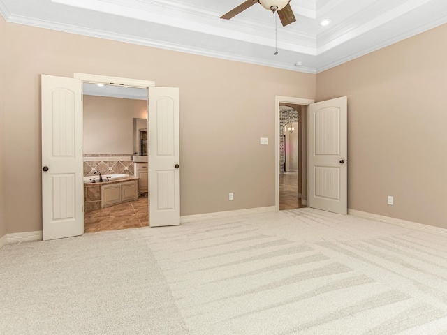 unfurnished bedroom with light carpet, ensuite bath, a tray ceiling, ceiling fan, and crown molding