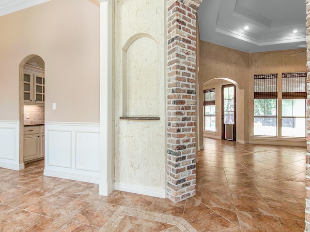 corridor with a tray ceiling and ornamental molding