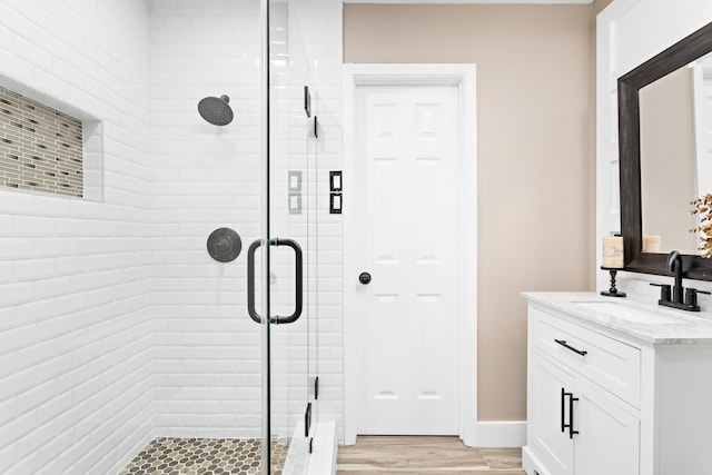 bathroom with an enclosed shower, vanity, and wood-type flooring