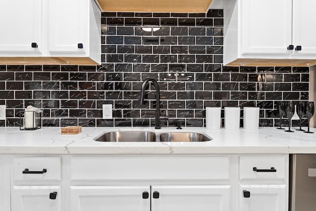 kitchen with light stone counters, white cabinetry, tasteful backsplash, and sink