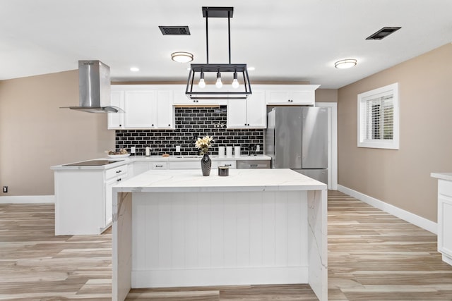 kitchen with decorative light fixtures, white cabinetry, island exhaust hood, stainless steel refrigerator, and a kitchen island