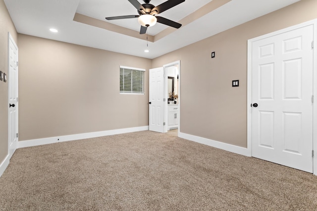 unfurnished room featuring ceiling fan, carpet floors, and a tray ceiling