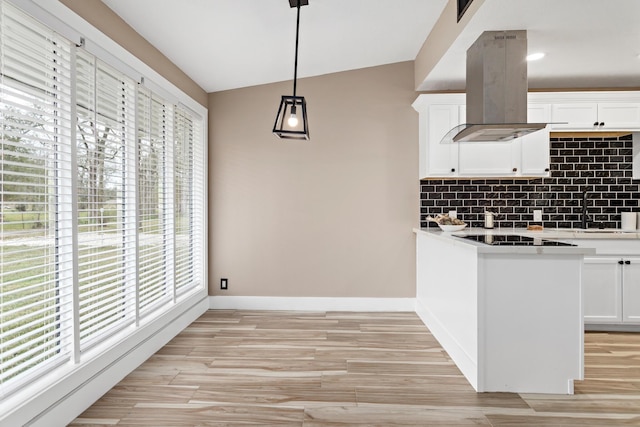 kitchen with island exhaust hood, hanging light fixtures, black electric stovetop, decorative backsplash, and white cabinets