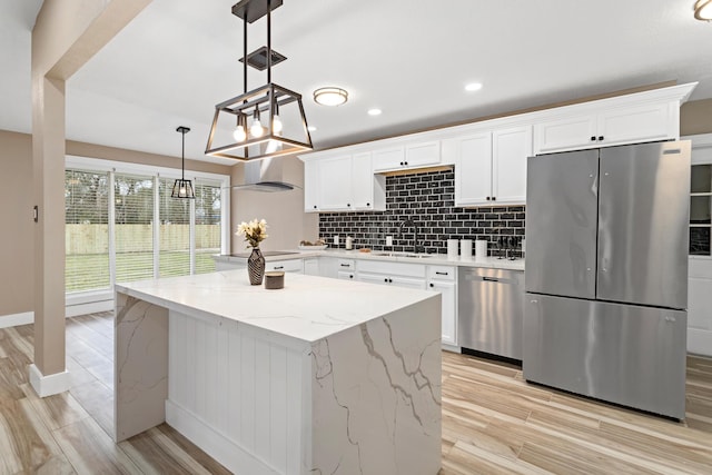 kitchen with stainless steel appliances, light stone countertops, white cabinets, decorative light fixtures, and sink