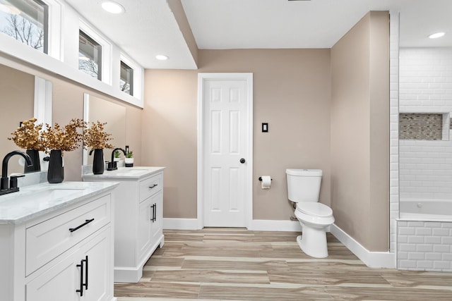 bathroom with a relaxing tiled tub, a wealth of natural light, vanity, and toilet