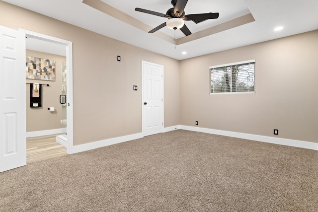 unfurnished room with ceiling fan, a raised ceiling, and carpet floors