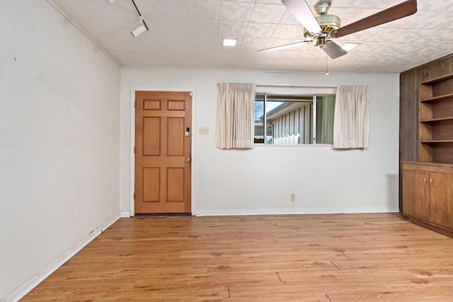 empty room with a ceiling fan, light wood finished floors, and baseboards