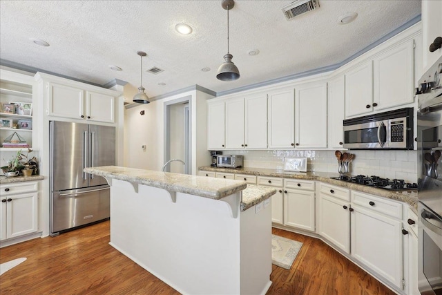 2175 Brewton Cir, Beaumont, TX 77706 - kitchen with appliances with stainless steel finishes, a textured ceiling, white cabinetry, and a breakfast bar