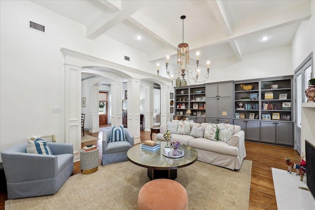 2175 Brewton Cir, Beaumont, TX 77706 - living room with ornate columns, arched walkways, wood finished floors, beamed ceiling, and a chandelier