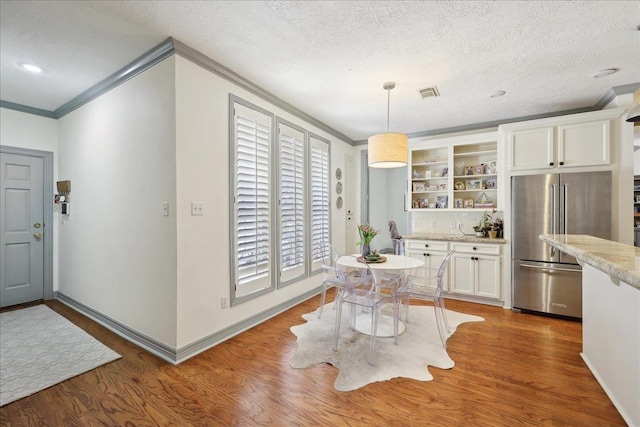 2175 Brewton Cir, Beaumont, TX 77706 - dining area featuring ornamental molding, wood finished floors, a textured ceiling, and baseboards