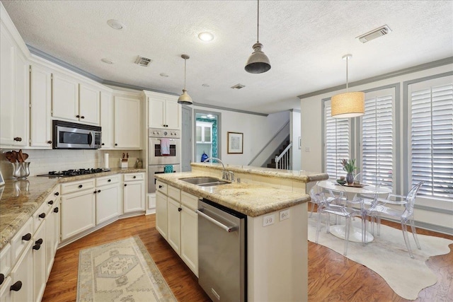 2175 Brewton Cir, Beaumont, TX 77706 - kitchen with stainless steel appliances, a sink, a textured ceiling, light wood finished floors, and decorative backsplash