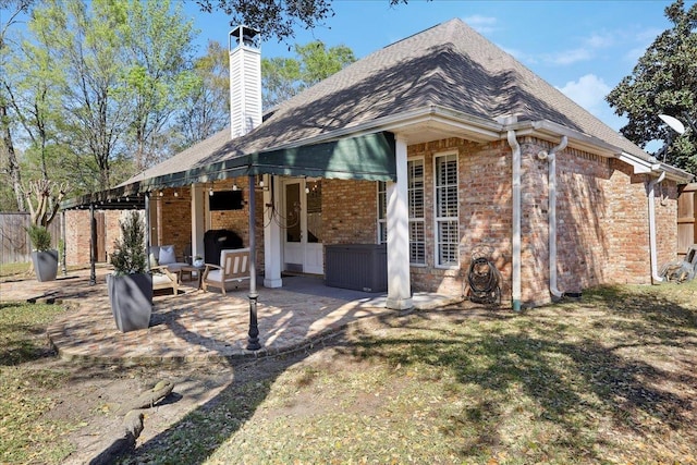 2175 Brewton Cir, Beaumont, TX 77706 - back of property featuring a patio, brick siding, a chimney, fence, and an outdoor living space