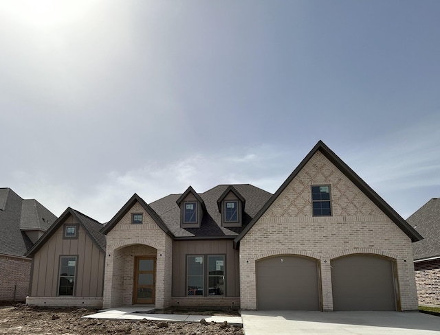 3547 Lily Ln, Beaumont, TX 77713 - view of front facade with board and batten siding, brick siding, a garage, driveway, and roof with shingles