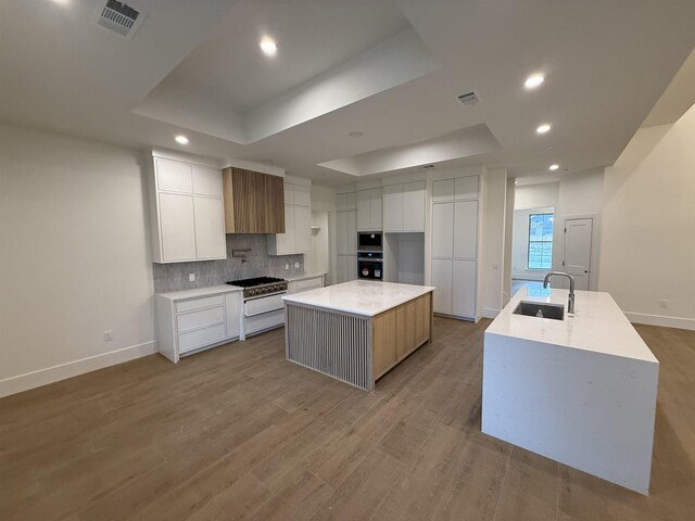 3547 Lily Ln, Beaumont, TX 77713 - kitchen featuring wall oven, a sink, a large island with sink, a tray ceiling, and recessed lighting