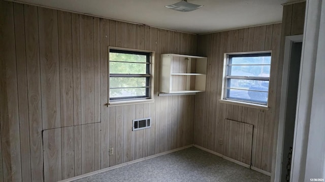 spare room with wooden walls and light colored carpet