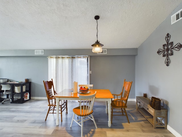 dining space with light hardwood / wood-style floors and a textured ceiling