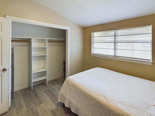 bedroom featuring vaulted ceiling, a closet, and light wood-type flooring