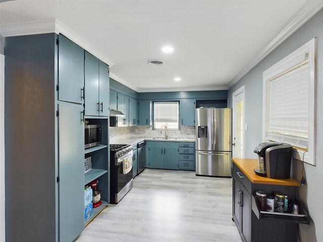 kitchen with sink, appliances with stainless steel finishes, tasteful backsplash, ornamental molding, and light wood-type flooring