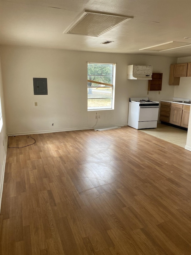 interior space with sink, white stove, light hardwood / wood-style floors, and electric panel