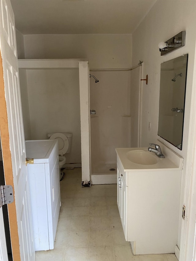 bathroom featuring washer / clothes dryer, a shower, vanity, and toilet