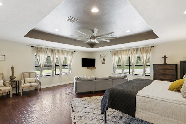 bedroom featuring ceiling fan, dark hardwood / wood-style flooring, and a raised ceiling