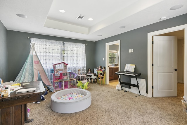 recreation room featuring a raised ceiling and light carpet