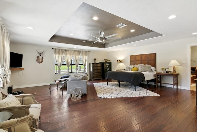 bedroom featuring dark hardwood / wood-style flooring, a raised ceiling, and ceiling fan