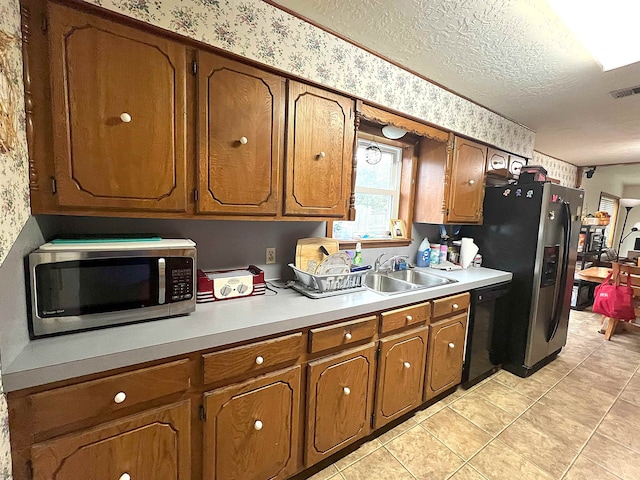 155 Hunters Ct, Lumberton, TX 77657 - kitchen featuring appliances with stainless steel finishes, a sink, brown cabinetry, light countertops, and wallpapered walls