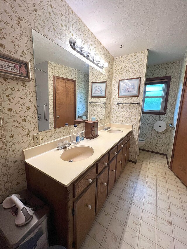 155 Hunters Ct, Lumberton, TX 77657 - bathroom with a textured ceiling, double vanity, wallpapered walls, and toilet