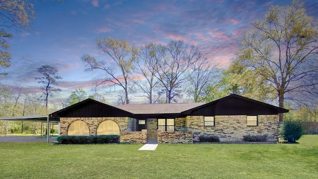 exterior space featuring brick siding, a yard, and an attached carport