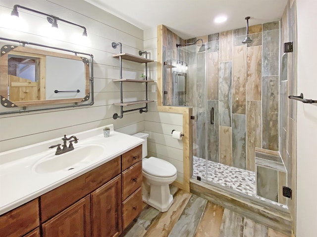 full bath featuring vanity, a shower stall, toilet, and wood finished floors