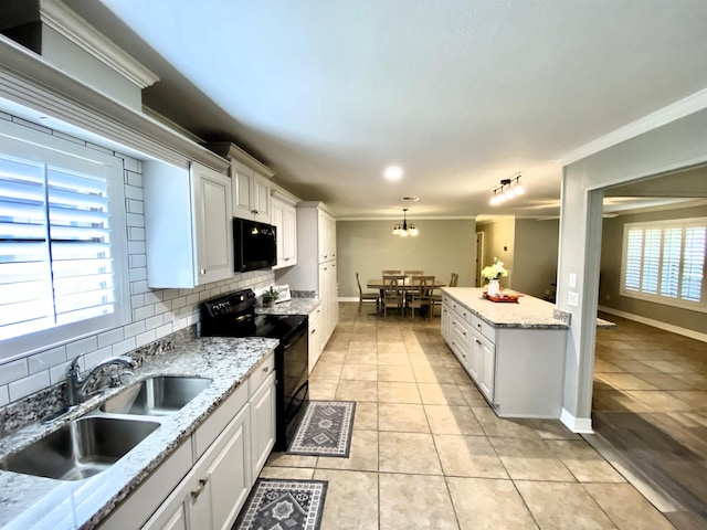 kitchen featuring crown molding, light tile patterned flooring, black appliances, and tasteful backsplash