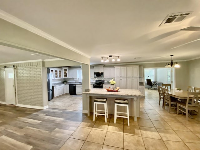 3900 Lakeview Cutoff, Vidor, TX 77662 - kitchen featuring black appliances, ornamental molding, a center island, a kitchen breakfast bar, and light stone counters
