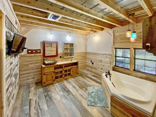 bathroom with double vanity, a garden tub, visible vents, wood finished floors, and wooden walls