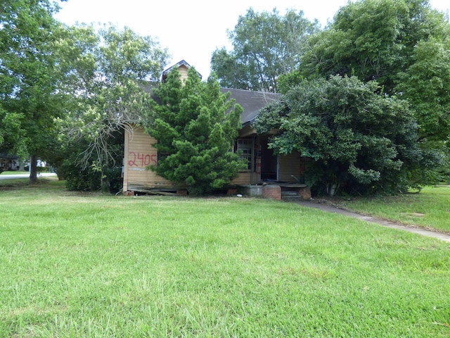 view of property hidden behind natural elements featuring a front yard