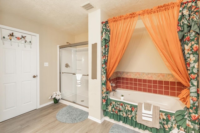 bathroom with shower with separate bathtub, wood-type flooring, and a textured ceiling