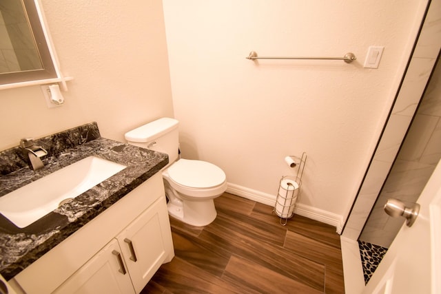 bathroom with hardwood / wood-style flooring, vanity, toilet, and walk in shower