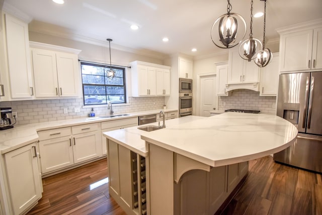 kitchen with appliances with stainless steel finishes, tasteful backsplash, sink, decorative light fixtures, and an island with sink