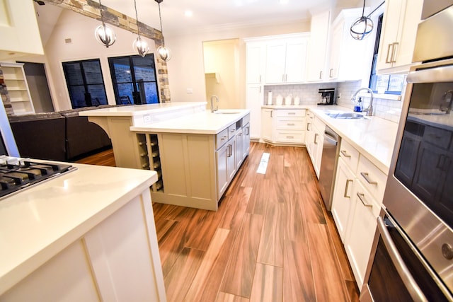 kitchen featuring a kitchen breakfast bar, sink, an island with sink, appliances with stainless steel finishes, and white cabinetry